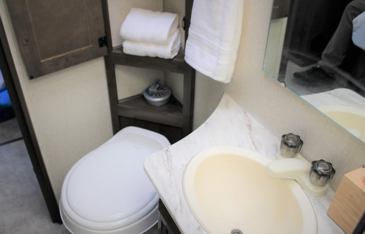 Foot pedal flushing toilet, wash sink, and bathroom cabinet for added storage.