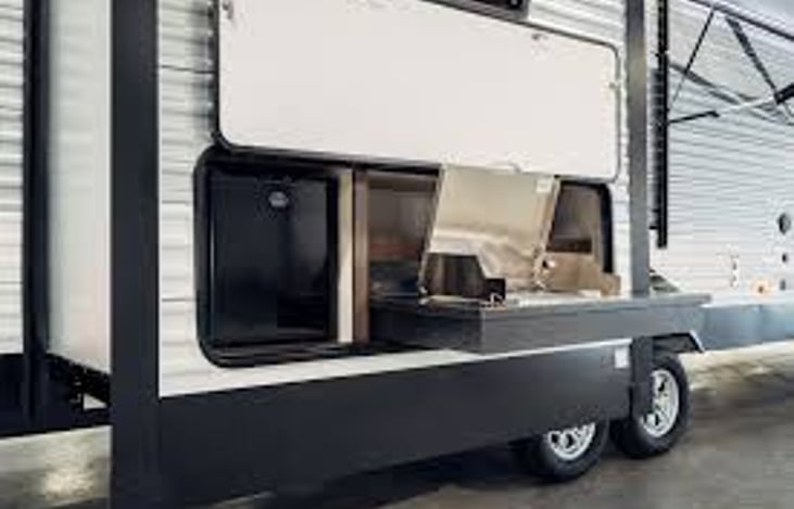 Cool outdoor kitchen complete with Blackstone type grill and refrigerator and water access