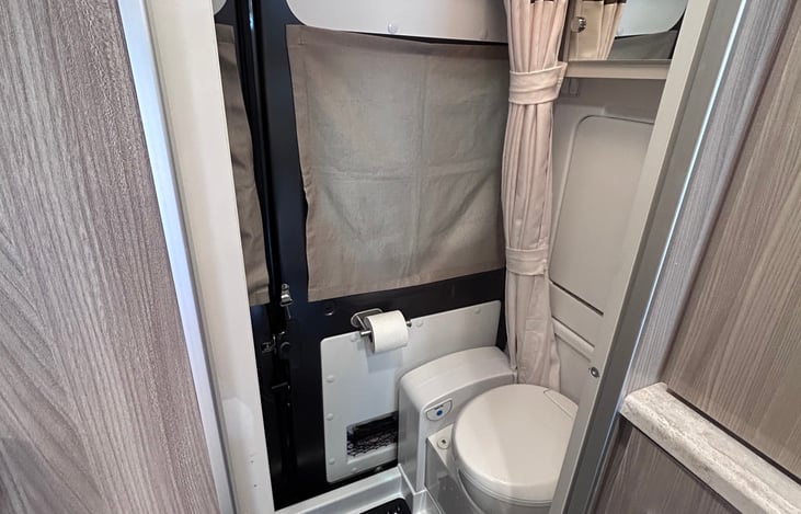 Bathroom, shower & fold down faucet, medicine cabinet & cassette toilet looking from inside coach.