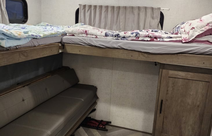 Rear bunkhouse with full sliding door, 2 upper fold down beds, and lower bench that folds down to another queen bed.