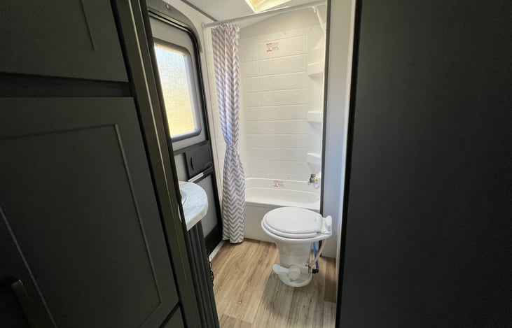 Bathroom located at rear of travel trailer. Includes exterior door, combo shower/tub - tub suitable only for small children, toilet, sink, mirror, and storage cabinets.
