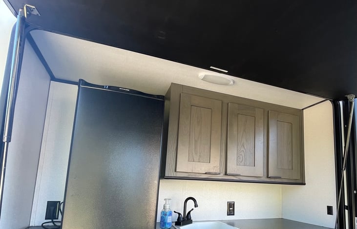 Outdoor kitchen equipped with mini fridge and propane stove with two burners