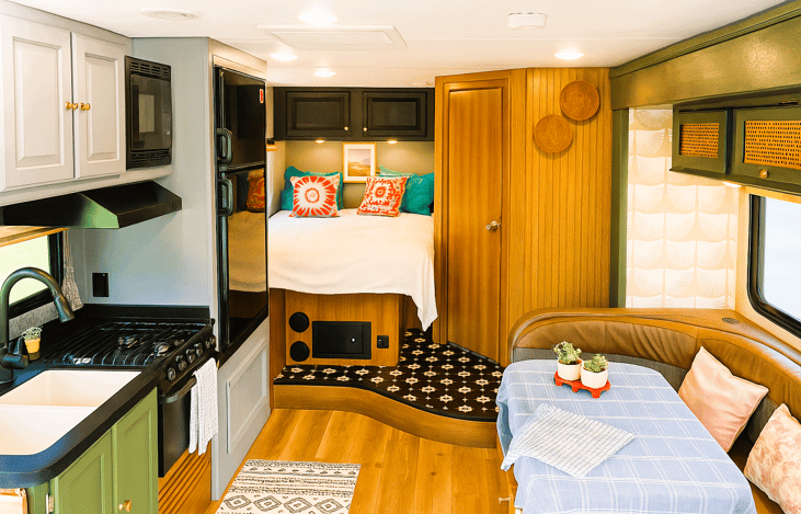 Modern interior with cozy bed and dinette — ideal for RV rentals with kids or pets.