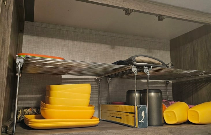 Over kitchen sink storage equipped with dishes for your use.  Smore skewers and coozies too!