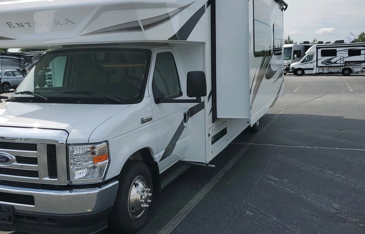 Driver-side slide-out containing dining table and theater seating. Aluminum running boards on the driver and passenger doors for ease of entry.