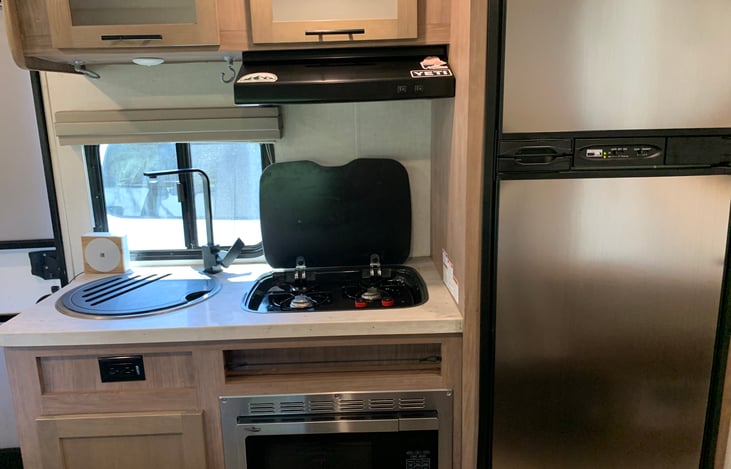 Propane stove lights with a lighter and has overhead vent fan