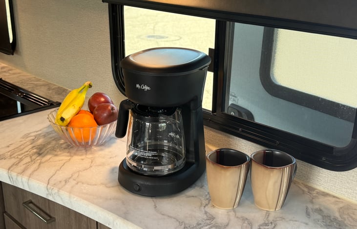 Coffee maker with 4 mugs, filters, and packets of sugar are also provided.