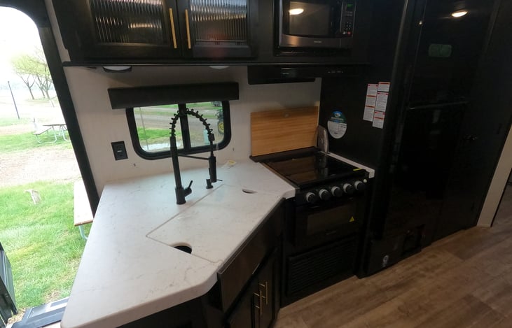 Functional kitchen with range, oven, microwave and stocked with toaster, coffee pot and all plate and utensils