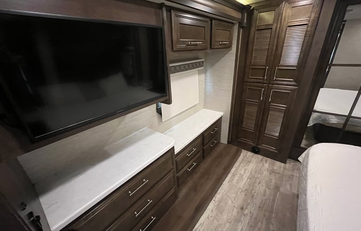 Dressers in bedroom with TV.