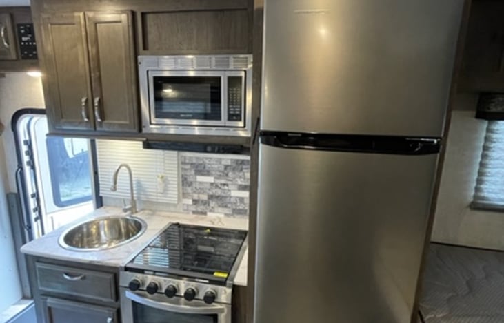 Kitchen complete with refrigerator, sink, 3 burner stove and oven and a microwave.