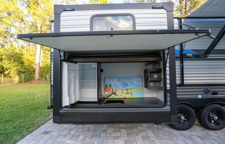 outdoor kitchen with refrigerator, sink, and storage.