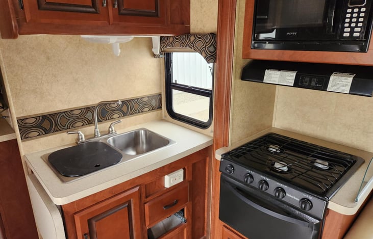 Stove and oven are gas, the sink has both hot and cold water. We have attached a rack for spices, a knife block and container to hold larger serving utensils. Microwave works great also.