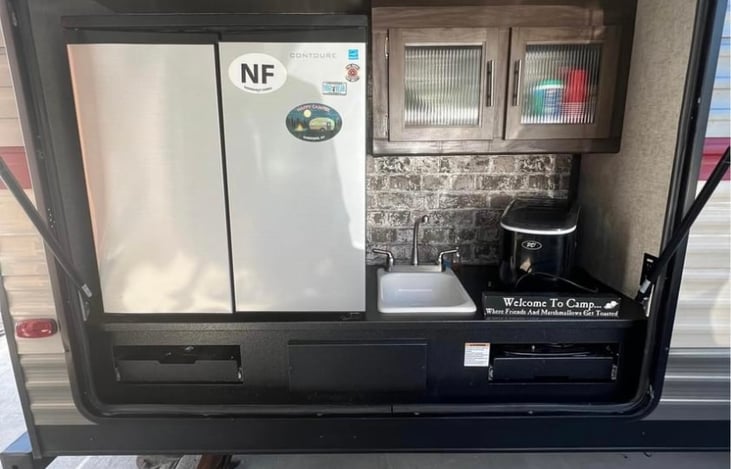 Outdoor kitchen with pull out stove top, drawers, cabinets, hot and cold sink, fridge and ice maker.