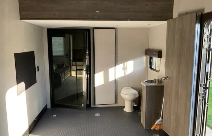 Toilet and sink in cargo/garage area has retrable walls and door for privacy. Rear door allows access to and from trailer without going through main living area.