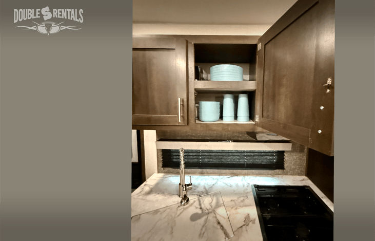 Stocked with dinnerware, cookware, coffee maker, and utensils.