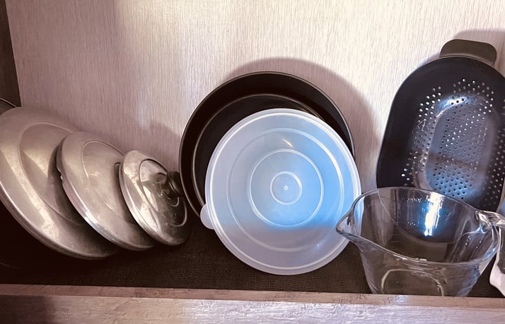 additional items in the pantry include lids for pots and pans, mixing bowls with lids, strainer, and glass mixing bowl with lid.