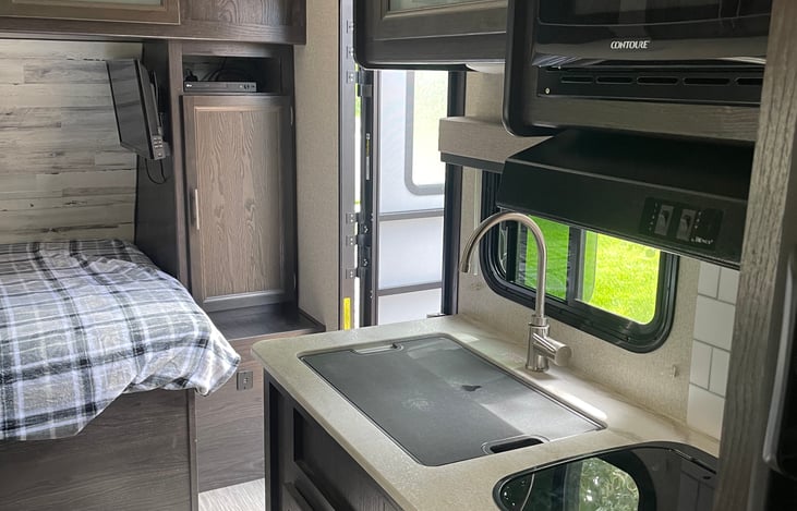 Fully stocked kitchen with sink, stove, microwave.