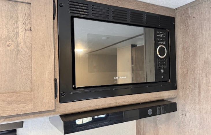 Microwave is in between the overhead storage and the pantry above the gas range.