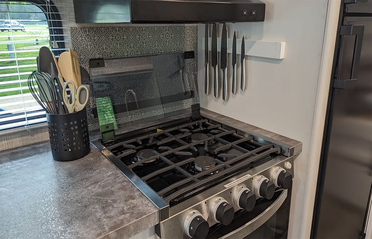 Three burner gas stove with a full set of new knives and cooking tools. The exhaust fan vents outside to help with heat and odors.