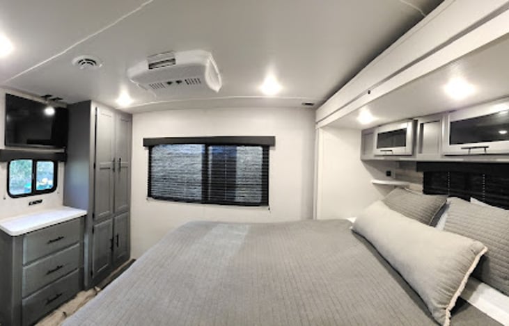 A look at the king bedroom entering from the living area.  Notice the ample storage drawers and cabinets, the wall mounted smart TV and the separate AC unit.