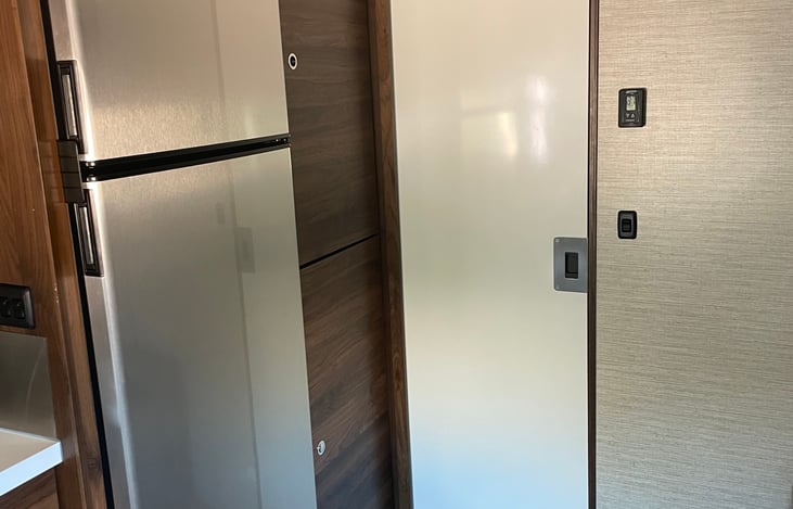 Bathroom pocket door in the closed position.  Note: full size fridge and freezer.