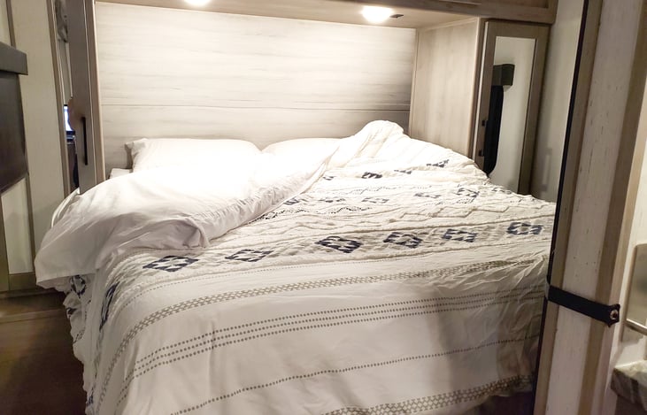 Queen Bed with dresser on both side and storage above.