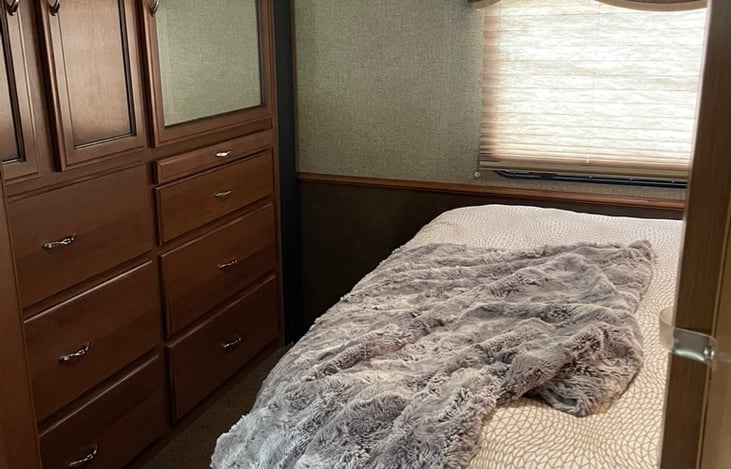 The bedroom has a whole wall of storage! The mirror and pull out counter are very handy for ladies. There is a cabinet for hanging items and this also houses a swing-out tv.