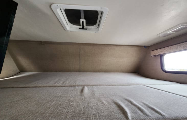 Huge overhead bunk with windows and a privacy curtain.