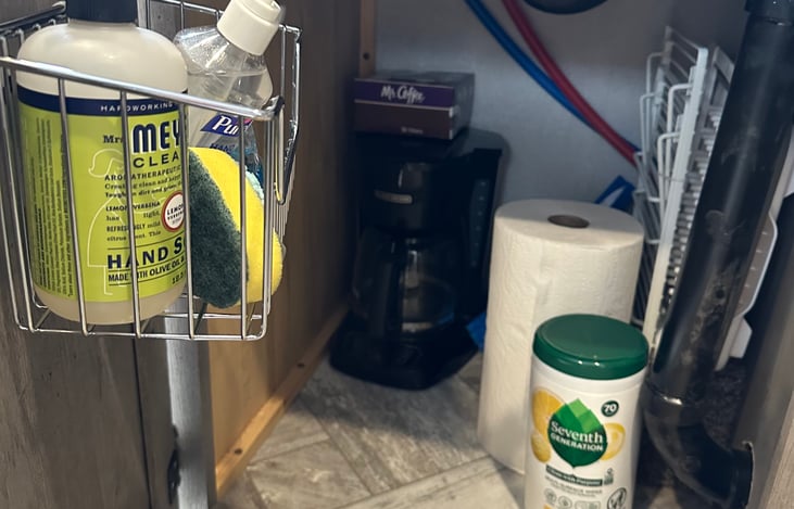 Basic cleaning supplies, coffee maker, broom and dust pan, and dish drying rack