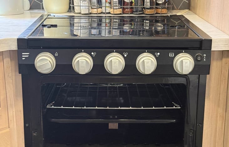 Three-burner propane stove with compact oven capable of preparing full meals, featuring easy-to-use ignition controls.