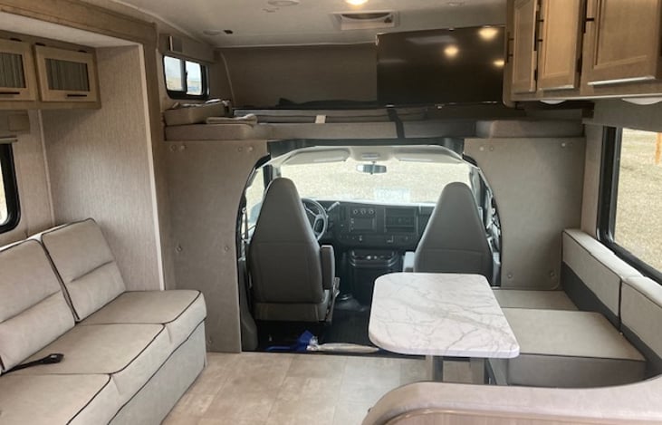 Living space with fold out couch, bunkbed and convertible kitchen table.
