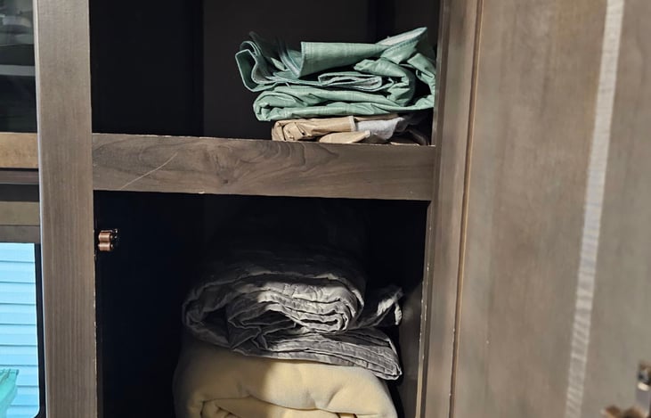 cupboard with extra blankets and tablecloth provided.