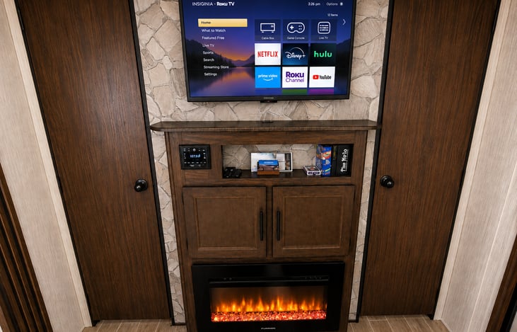 The entertainment center features a Smart TV, stereo system, fireplace, plus books and games—ALL included STANDARD with every RV rental at NO additional charge.