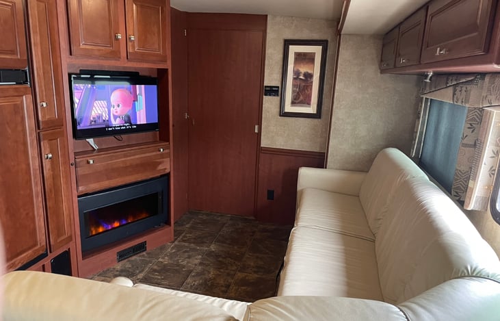 Wrap-around couch with TV and electric fireplace.