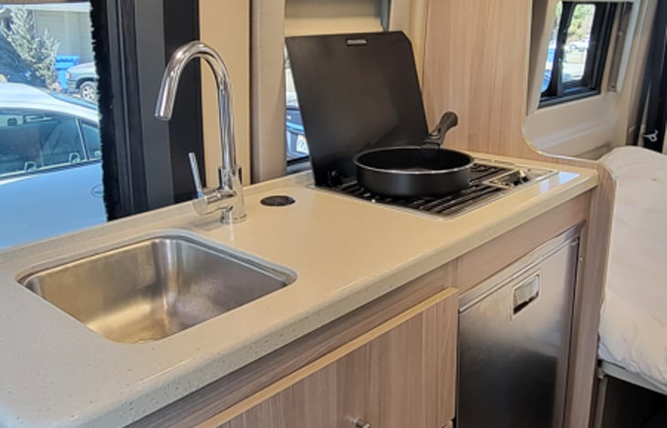 Kitchen area with sink, stove with two burners, fridge, and microwave.