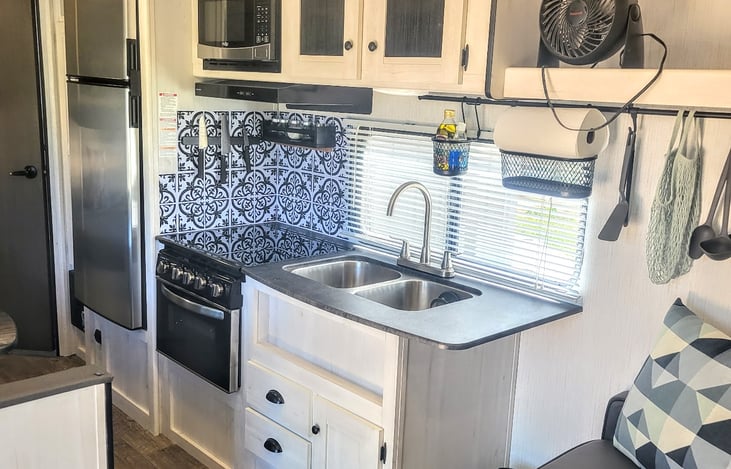 Huge doublebowl kitchen sink, plenty of storage in uppers and lower drawers.  Garbage and recycling baskets in bottom cabinet.  Convenient custom rack to hange utensils, paper towels, dish soap & more