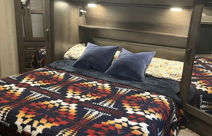 Front master bedroom, Queen size bed, smart TV, Closets on both sides of the bed, 3 overhead storage compartments, and an additional closet with 2 drawers