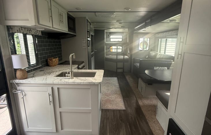 This is a view looking towards the bunk beds. In between is the kitchen, dinette, living room with TV and bathroom in the back left.
