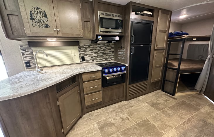 Large kitchen. Huge under sink space with garbage can and bags and cleaning supplies. 3 burner stove with small oven. Above sink has all plates, paper towels and assorted kitchen ware.