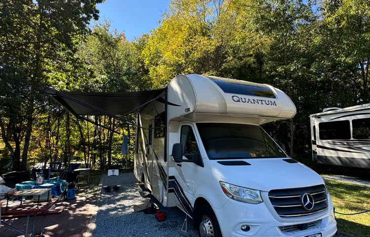Exterior of the rig with awning fully extended, creating amble outdoor covered seating space, as well as protecting the entry area.