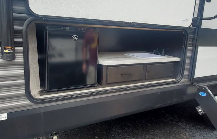 Outdoor Kitchen: Small fridge for drinks, sink has hot and cold water. Outdoor grilling Utensils in drawer.