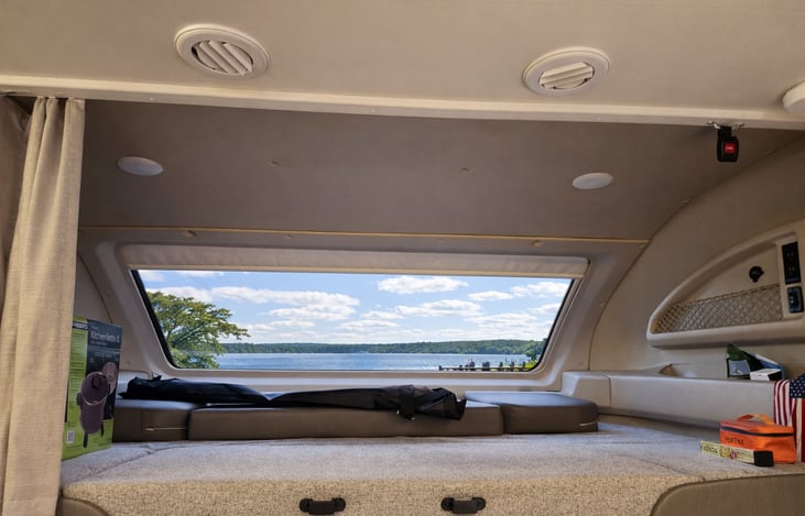 Overhead bunk with 750lb capacity, safety net, electric outlets, panoramic window with power shade and privacy curtains