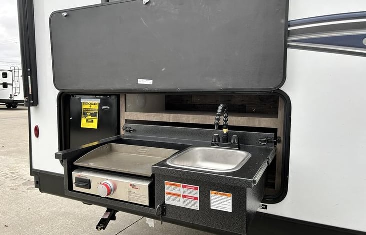 Outdoor kitchen with storage space, sink, grill and fridge