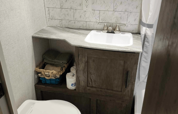 Bathroom includes sink, towels, and foot flush toilet.