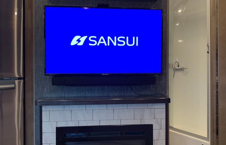 Main solan TV with storage above, & fireplace.