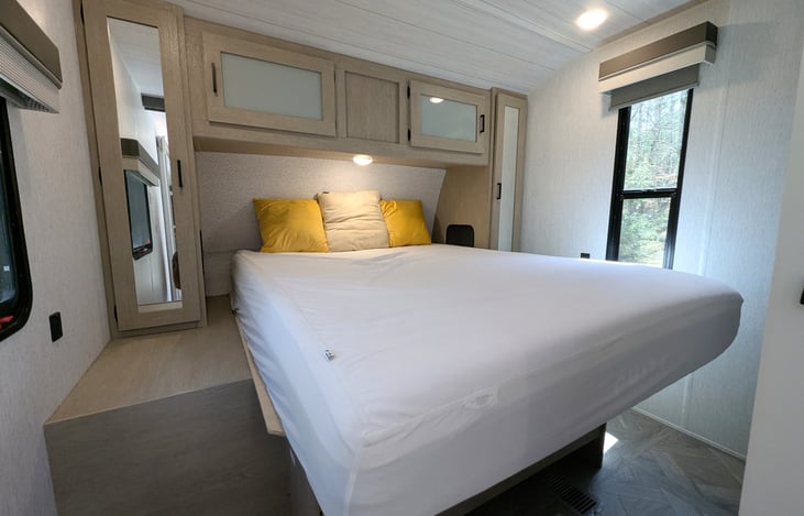 Bright and modern interior with a Custom King bed, double bunks, and a Versa-Lounge slide. Features a 30” fireplace, panoramic windows, 10.7 cu ft fridge, and a walk-in closet. Luxury camping at its f