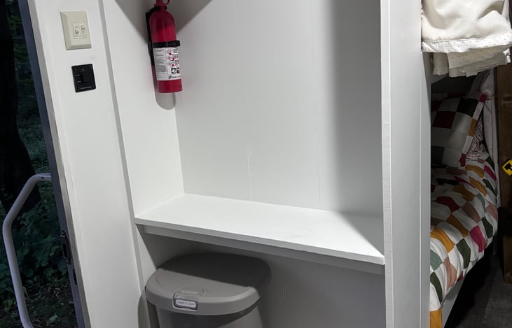 Upon entering, trash, coat hangers, fire extinguishers, and radio. The button for the automatic awning located on the wall along with light switches.