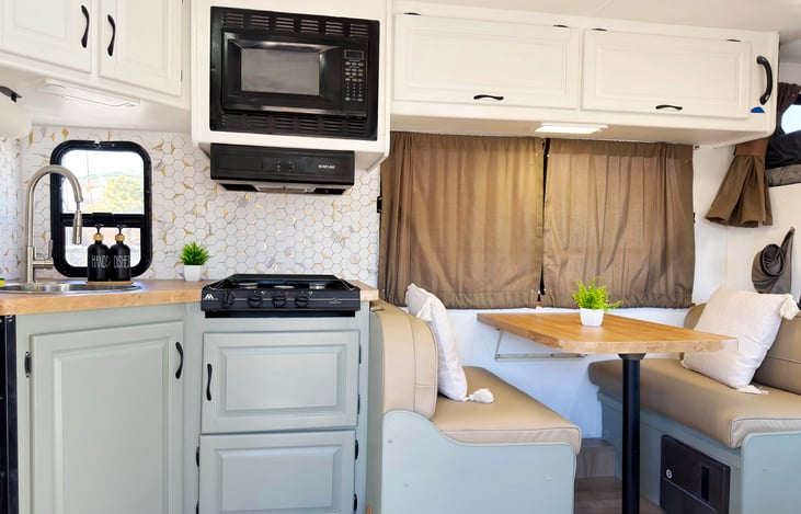 Share meals and laughs in this comfy dining nook — part of a glamping-style, event ready RV rental that sleeps 6 and offers a true home-on-the-road vibe
