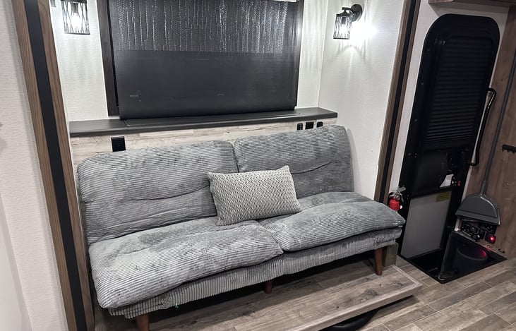 TV is on an elevator behind the futon