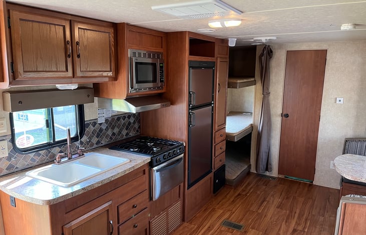 Kitchen area with 3 burner stovetop, oven, microwave, fridge n freezer with 3 separate bunks in the back